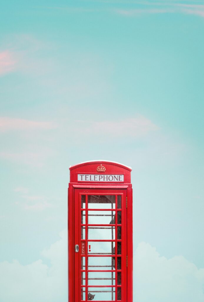 Minimalist photo of a red telephone booth in London with a clear blue sky.