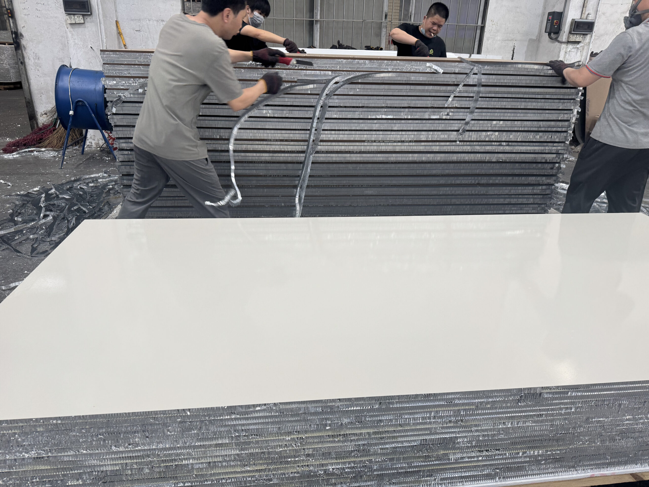 Factory workers handling aluminum honeycomb panels during production
